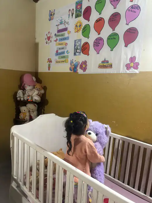 Una niña abrazando su peluche en la cuna