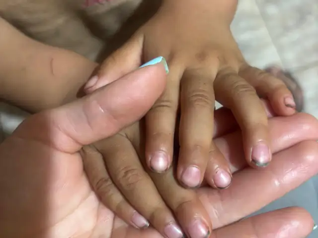 La mano de una cuidadora sosteniendo la de un niño
